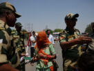 A military personnel with border security force checks passport of pakistani citizens as they prepare to leave india, at the attari wagah border crossing near amritsar